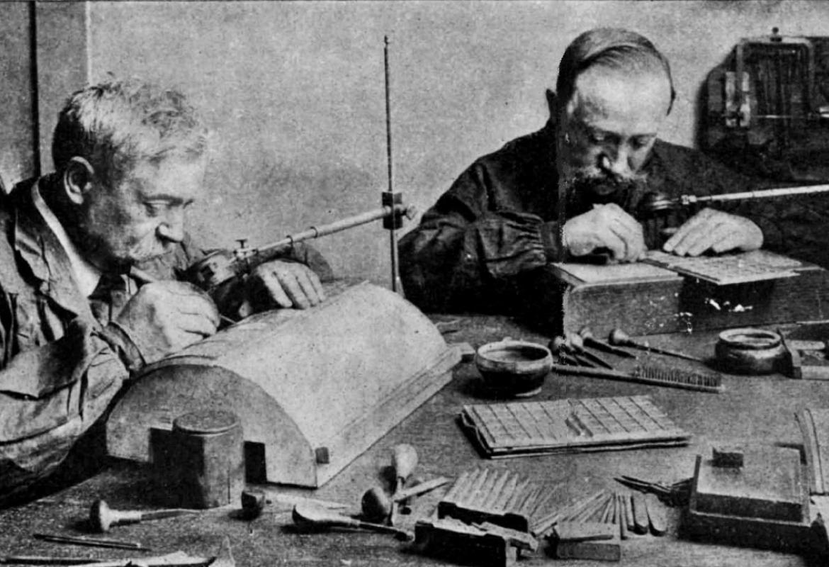 1. Ultimes retouches des plaques à partir desquelles sont imprimés les timbres-poste avec sur la table les outils bien connus des graveurs : un jeu de burins montés sur des manches en bois en forme de poire, des pointes sèches, une loupe, etc.